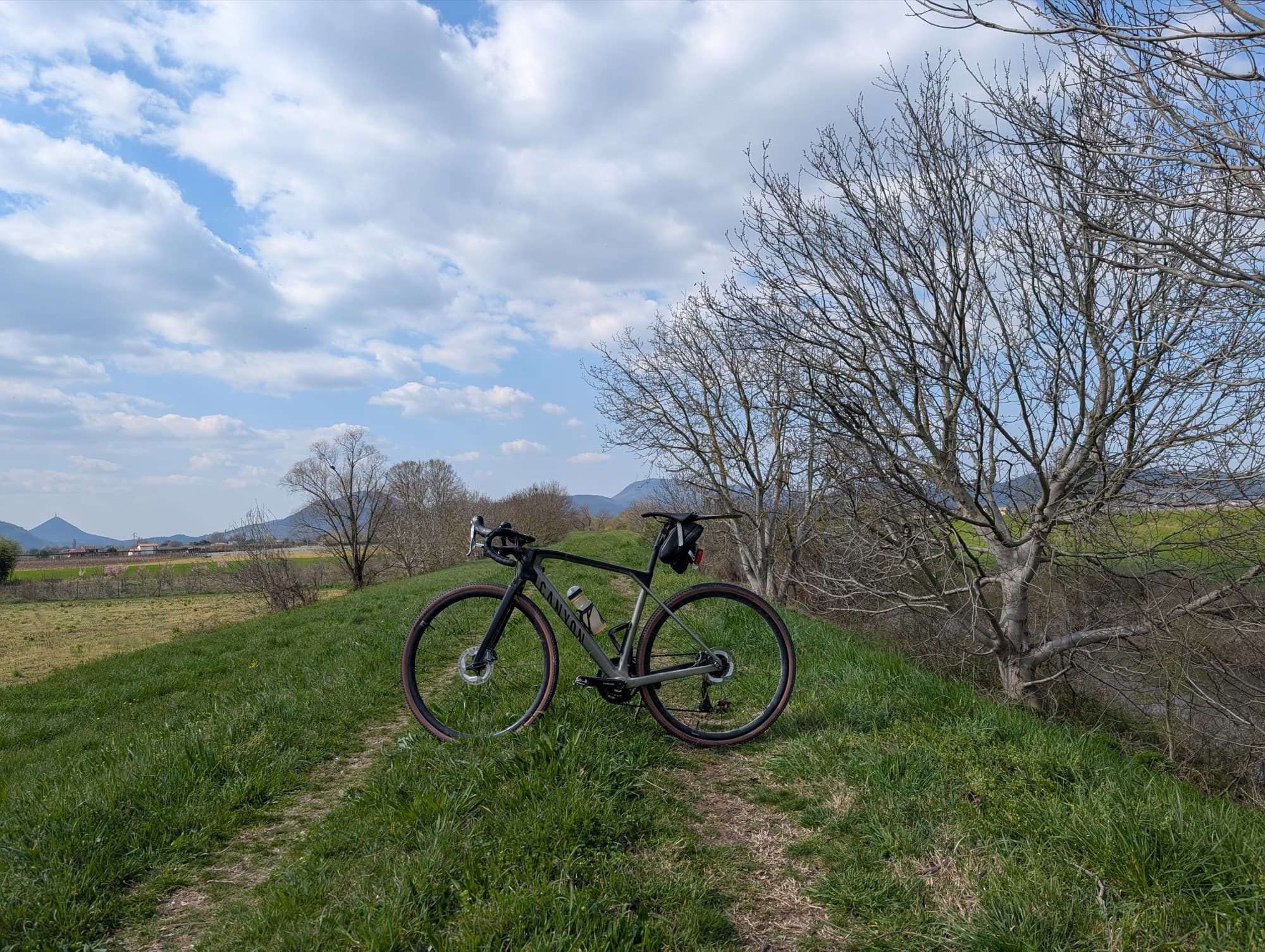 Bici gravel su un argine erboso, con i colli sullo sfondo